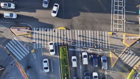 Busy-traffic-intersection-with-cars-and-pedestrians-on-crossing,-aerial-top-down