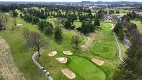 Schöner-Grüner-Golfplatz-Mit-Waldbäumen-Und-Spieler-Mit-Golfwagen-Im-Sonnenlicht