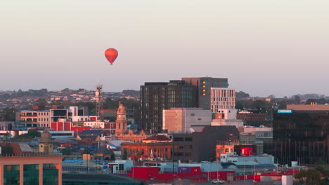 Luftaufnahme-Eines-Heißluftballons,-Der-Am-Frühen-Morgen-über-Der-Stadt-Schwebt