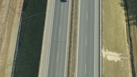 Aerial-view-of-a-single-car-on-a-highway,-emphasizing-open-road-and-travel