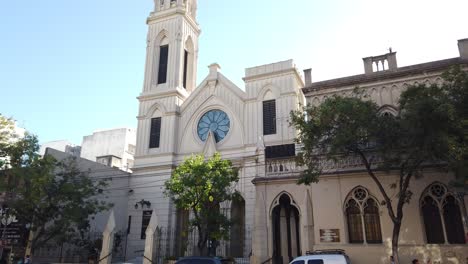 Fachada-De-Entrada-De-La-Iglesia-De-San-Cristóbal-En-Las-Calles-De-La-Ciudad-De-Buenos-Aires,-Argentina,-Tráfico-De-Automóviles-Y-Luz-Solar-En-El-Horizonte-Diurno,-Peatones-Caminando-Por-Un-Punto-De-Referencia-Religioso-En-La-Ciudad