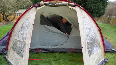 A-happy-man-opening-unzipping-tent-door-leaving-tent-and-appreciating-the-freedom-of-nature