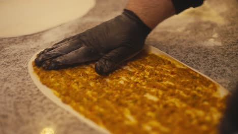 Close-up-of-hands-preparing-traditional-kebab-pizza-in-a-shop,-warm-tones