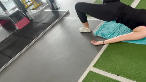 Fit-woman-in-gym-clothes-doing-core-exercises-legs-at-the-gym-floor-mat