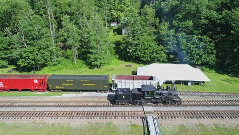 Luftaufnahme-Einer-Antiken-Shay-Dampflokomotive,-Die-An-Einem-Sonnigen-Sommermorgen-In-Zeitlupe-Rückwärts-Fährt,-Um-Sich-Einem-Bahnhof-Zu-Nähern