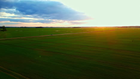 Drones-Aéreos-Avanzando-En-Movimiento-Sobre-Tierras-De-Cultivo-Verdes-Con-El-Sol-Saliendo-Al-Fondo-Durante-La-Mañana