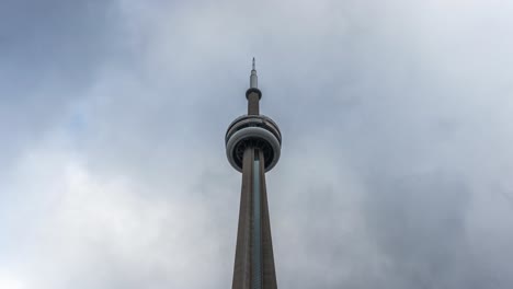 Timelapse-of-clouds-moving-over-top-of-Toronto’s-CN-Tower,-tilt-down