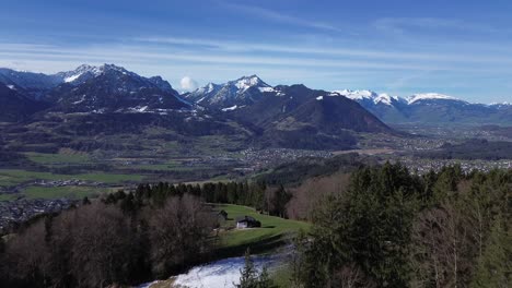 Drohnen-Steigen-In-Den-Himmel-Auf-Und-Fliegen-über-Hütten-Und-Wäldern-Mit-Herrlichem-Blick-über-Die-Winterliche-Berglandschaft-Mit-Schneebedeckten-Bergen-An-Einem-Sonnigen-Tag