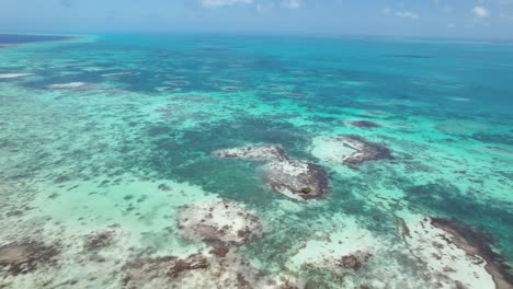 Aerial-360-pan-over-Los-Roques'-vibrant-green-waters-and-mangroves,-daylight
