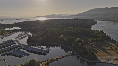 Vancouver-BC-Canada-Aerial-v45-flyover-the-harbour-capturing-yacht-club,-urban-oasis-of-Stanley-park,-West-mountain-views-and-shimmering-sunlight-on-the-water---Shot-with-Mavic-3-Pro-Cine---July-2023