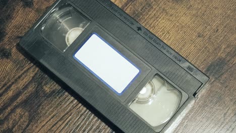 Manos-Pegando-Una-Etiqueta-Vacía-En-Blanco-En-El-Frente-De-Una-Cinta-Vhs-Vintage