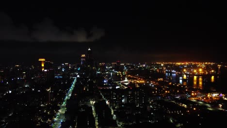 Nighttime-aerial-view-of-a-bustling-cityscape-with-illuminated-streets-and-buildings-along-a-river