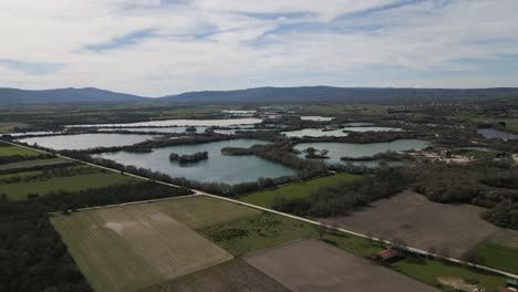 Panoramic-aerial-overview-of-country-road-and-agricultural-farm-fields-by-ancient-Antela-lagoon-Areeiras-da-Limia-in-Xinzo-de-Limia-Ourense