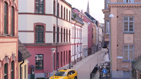 Aerial-between-buildings-in-Malmo-Gamla-staden-as-taxi-drives-down-street