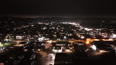 El-Dron-Vuela-De-Lado-A-Través-Del-Paisaje-Urbano-De-Una-Pequeña-Ciudad-Por-La-Noche-Mostrando-Muchas-Luces-De-La-Ciudad-Mientras-Los-Autos-Circulan-Por-Las-Carreteras