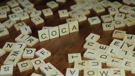 Male-right-hand-makes-word-COCAINE-using-wooden-Scrabble-letter-tiles