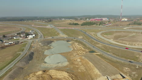Expansive-aerial-view-of-a-large-highway-interchange-under-construction-with-surrounding-landscape