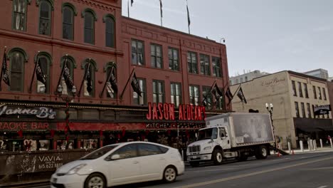 Bars-on-Broadway-Street-in-Nashville,-Tennessee-during-the-day-with-handheld-shot-panning-left-to-right