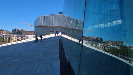 Oslo-Opera-House,-Norway,-Mirror-Reflection-From-Glass-Wall,-People-Walking-by-Landmark