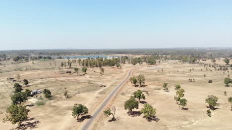 Aerial-wide-shot-of-barren-land-with-asphalt-road-in-Charu-village-in-Chatra,-Jharkhand,-India