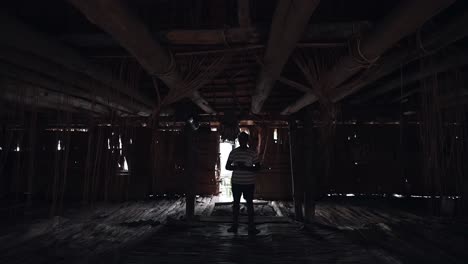 Entering-inside-point-of-view-wooden-house-with-dark-skin-man,-empty-hut