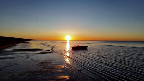 An-unusually-beautiful-sunset-in-the-ocean-reveals-the-beauty-of-the-sandy-beach-terrain-and-in-the-distance-there-is-a-fisherman's-boat-full-of-fishing-gear
