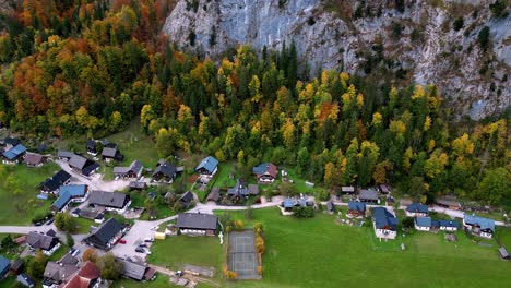 Pequeño-Y-Remoto-Pueblo-Ubicado-Entre-Colinas-Verdes-Y-Montañas-Cubiertas-De-Nieve,-Con-Un-Río-Sinuoso-Que-Serpentea-A-Través-Del-Valle.