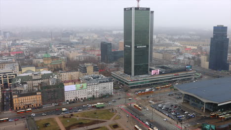 Traffic-driving-past-high-rise-building-in-Warsaw-downtown,-Poland,-high-angle-view