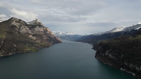 Aerial-pan-above-calm-placid-lake-in-Walensee-Switzerland-above-steep-cliffs