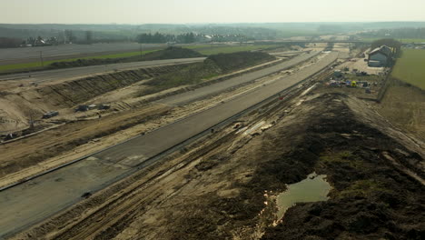 Expansive-aerial-view-of-a-highway-under-construction,-showing-machinery-and-partially-completed-roadways
