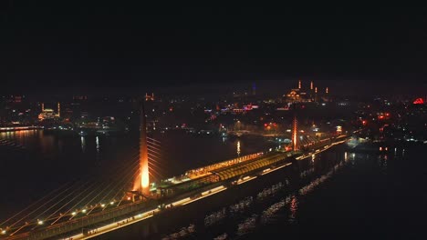 Drone-flight-around-illuminated-cable-stayed-metro-bridge-in-Istanbul-at-night,-Haliç-station-connecting-Eminönü-and-Beyoğlu-districts