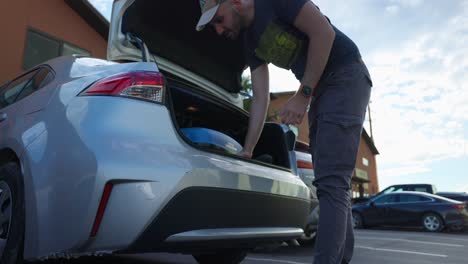 Male-Taking-Out-Luggage-Suitcase-Out-Of-Car-Trunk-Boot-In-Hotel-Car-Park