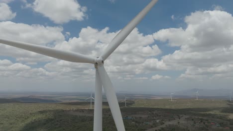 Close-up-of-a-turbine-spinning-at-a-wind-farm-with-other-turbines-visible-in-the-distance