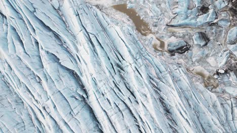 Earth-blanketed-in-snow-and-ice-presents-serene-and-ethereal-scenery,-top-down-aerial-view-of-glacier