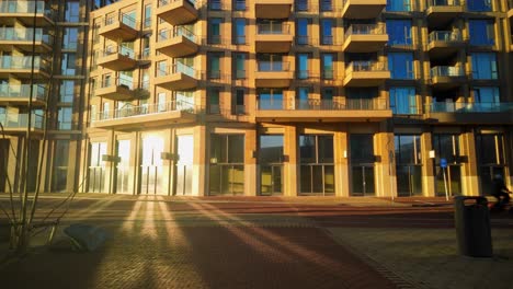 La-Luz-Del-Sol-Reflejándose-En-El-Vidrio-En-Un-Nuevo-Y-Moderno-Edificio-Residencial-En-La-Plaza-Con-Persona-Y-Bicicleta.