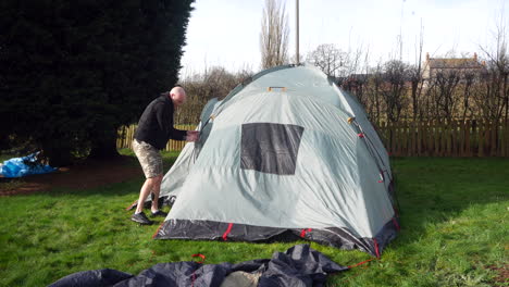 Ein-Mann-Baut-Auf-Einem-Campingplatz-Auf-Dem-Land-Ein-Zelt-Auf-Und-Befestigt-Stangen