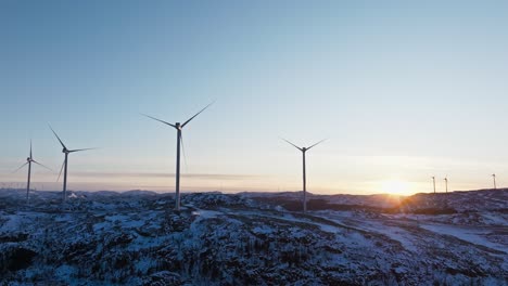 Windmühlen-In-Den-Schneebedeckten-Bergen-Von-Bessaker,-Norwegen-Bei-Sonnenuntergang---Drohnenaufnahme