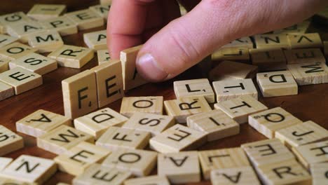 On-table-top,-hand-forms-word-FEAR-in-scrabble-letter-tiles,-close-up