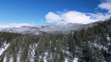 Aerial-ascent-of-roads-and-pine-trees-in-Lake-Tahoe-wilderness-with-mountains-in-the-background