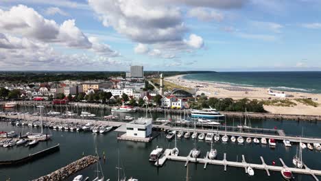 lighthouse-on-the-beach,-small-harbor-with-many-boats,-beautiful-beach-with-waves,-baltic-sea,-warnemünde,-drone