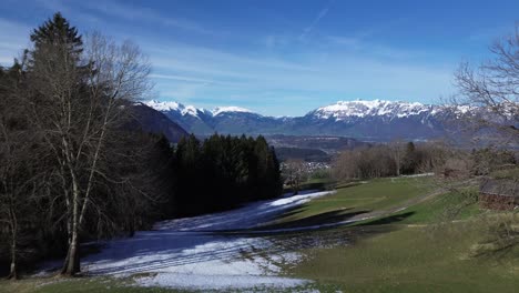 Drone-shot-of-huts-in-the-mountains-with-amazing-view-over-winter-mountain-landscape-with-snowcapped-mountains-on-a-sunny-day-in-Austria