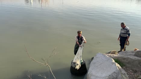 a-local-people-fisherman-in-middle-east-alone-fishing-by-handmade-net-stand-in-stone-beach-platform-traditional-skill-of-catch-fish-from-the-sea-in-the-beach-Caucasus-region-in-harbor-fresh-seafood