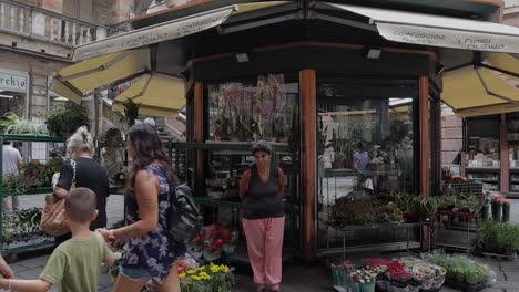 Slow-motion-shot-of-florist's-shop-with-people-walking-through-the-foreground