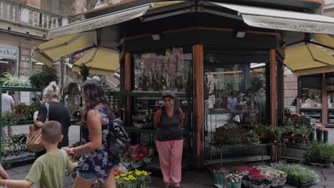 Toma-En-Cámara-Lenta-De-Una-Floristería-Con-Gente-Caminando-En-Primer-Plano