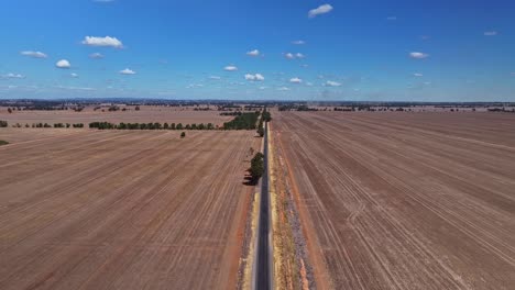 Straight-country-road-slicing-through-a-vast-brown-field-in-Yarrawonga-Victoria-Australia