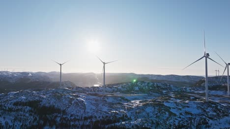 Turbinas-Eólicas-Al-Amanecer-Sobre-Montañas-Nevadas-Cerca-Del-Pueblo-De-Bessaker-En-Noruega