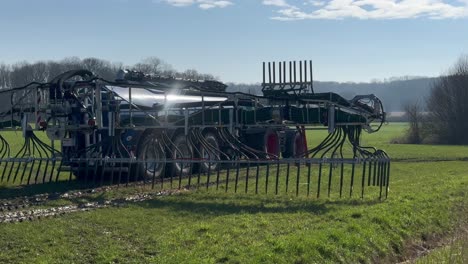 Große-Landwirtschaftliche-Maschinen-Traktor-Verbreiten-Gülle-Auf-Weide-Acker-Im-Frühjahr