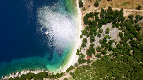 Overhead-orbiting-drone-shot-of-Foki-Beach,-a-secluded-public-resort-near-the-village-of-Fiskardo,-located-in-the-island-of-Kefalonia,-Greece