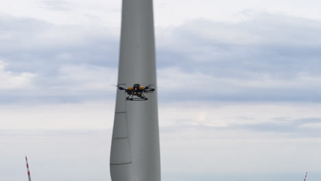 Shot-of-a-survey-drone-inspecting-a-wind-turbine-within-a-large-scale-energy-generation-farm