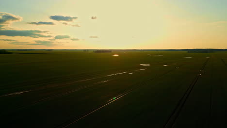 Aerial-footage-of-fertile-lush-green-farmlands-glistening-in-bright-sunshine,-orbit-shot